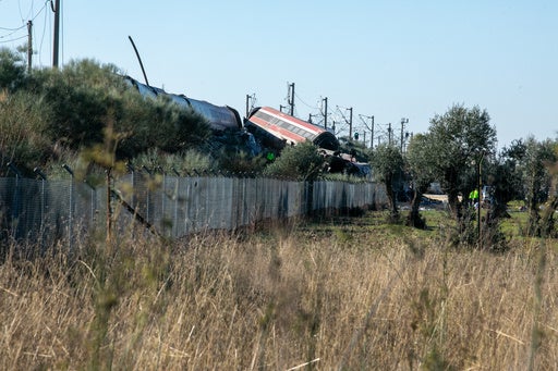 Rescue workers at the scene of a train collision in central Spain, with damaged train cars visible.